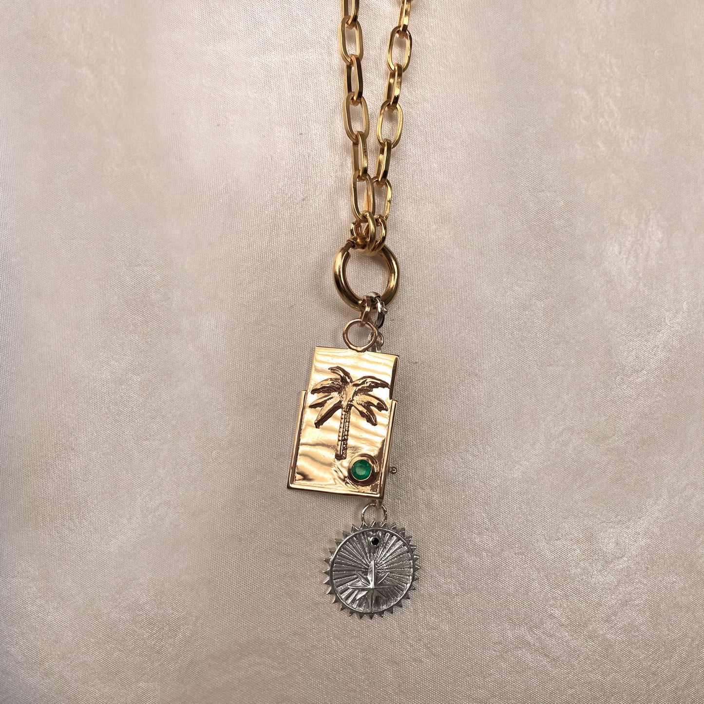 bold gold chain and layers of medallions and charms with colombian emeralds